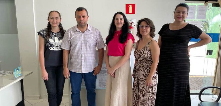 115ª ZE conscientiza estudantes sobre a importância do alistamento eleitoral Fotografia de quatro mulheres e um homem posando sorrindo em uma sala com paredes brancas. Ao re...