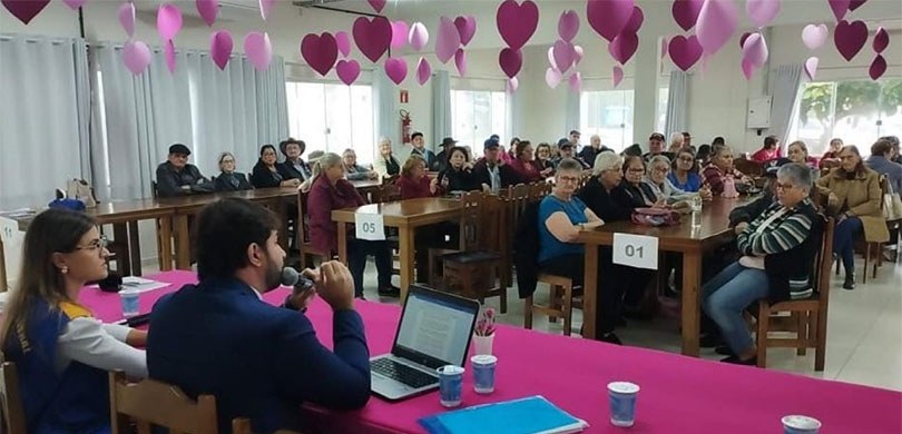 131ª Zona Eleitoral de Barracão incentiva o voto maduro nas Eleições 2022 A fotografia mostra uma reunião com várias pessoas sentadas em mesas distribuídas em um salão de...