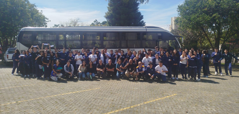 Fotografia de um grupo de aproximadamente 60 pessoas, majoritariamente jovens, posando em frente...
