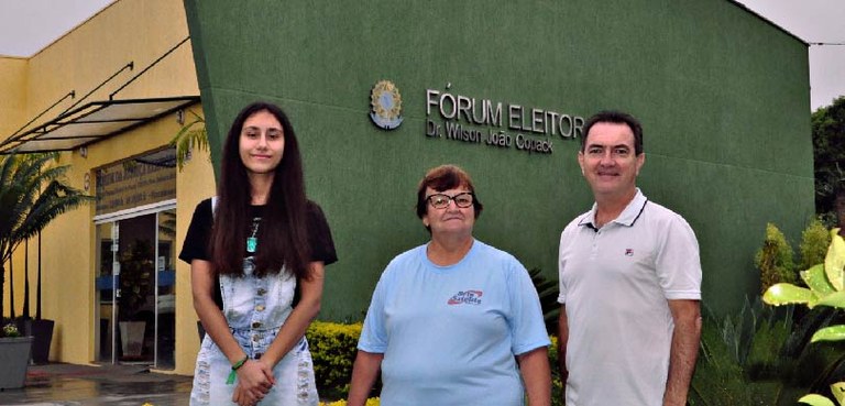 Fotografia de duas mulheres e um homem posando sorrindo em frente ao Fórum Eleitoral Dr. Wilson ...