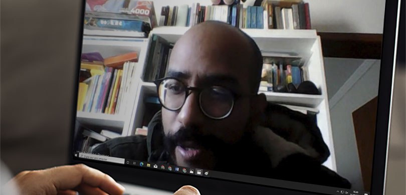 Fotografia da tela de um notebook. É possível ver um homem durante uma reunião por videoconferên...