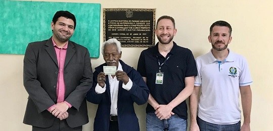2019-11-12-eleitor-mais-velho-trepr fundo amarelo com quatro homens posando para foto em primeiro plano