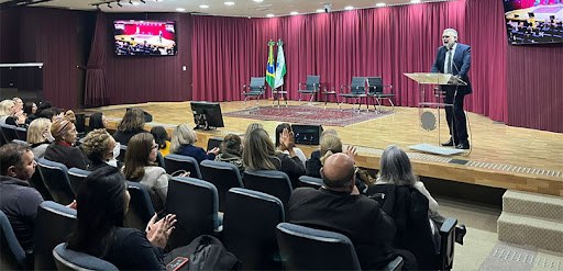 “A luta por direitos iguais é continua” diz presidente Coimbra de Moura em evento sobre a participação das mulheres na política Fotografia de um homem falando em um púlpito no palco de um auditório. É possível ver parte da p...