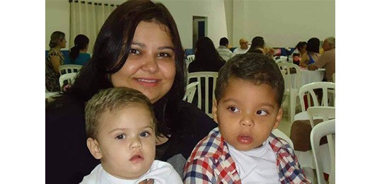 Foto de uma mulher sorrindo e duas crianças em seu colo