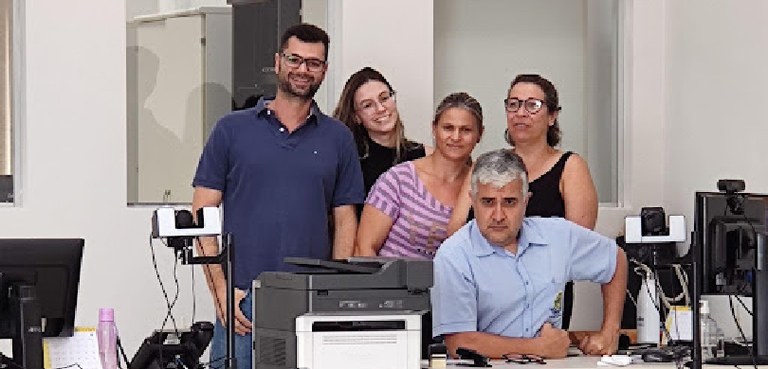 77ª Zona Eleitoral comenta sobre as disputas políticas acirradas em cidades do norte paranaense Fotografia de cinco pessoas, três mulheres e dois homens, posando sorrindo. Um dos homens aparec...