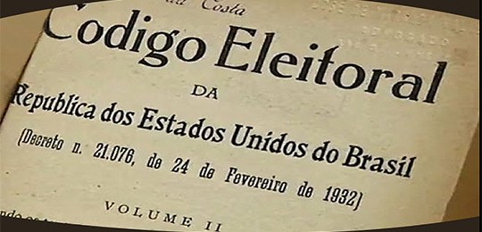 Fotografia da capa do Código Eleitoral brasileiro. O fundo é uma folha já amarelada, ao centro é...