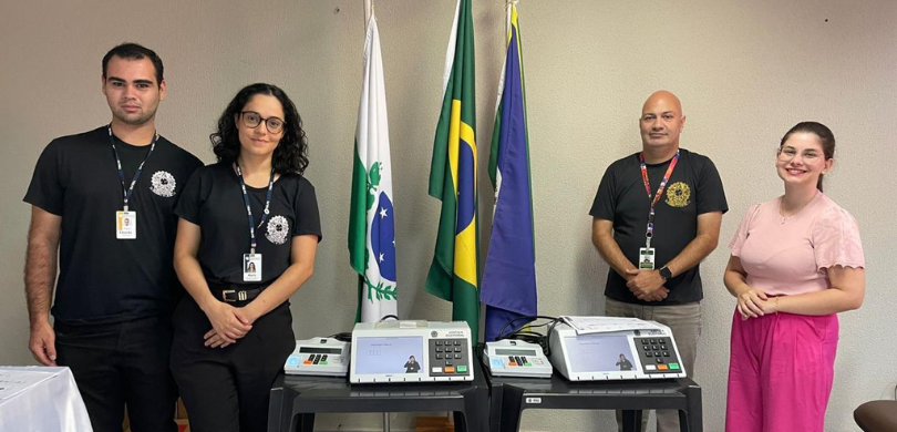 Fotografia de quatro pessoas, dois homens e duas mulheres, posicionados em pé para um registro o...