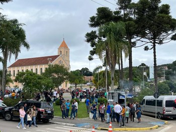 foto de um grupo de pessoas em pé, olhando para a câmera. Elas estão no pátio de uma escola 
