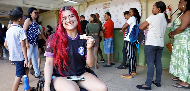 fotografia de uma eleitora com deficiência utilizando uma cadeira de rodas. Ela está posando sor...