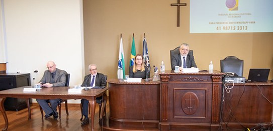 Um homem, que veste terno, está falando em um púlpito enquanto uma plateia o assiste.