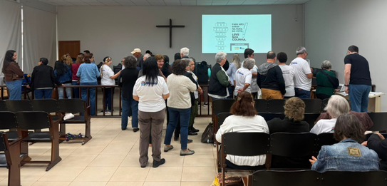Fotografia de cinco pessoas, quatro homens e uma mulher, em uma sala clara. Dois rapazes com col...