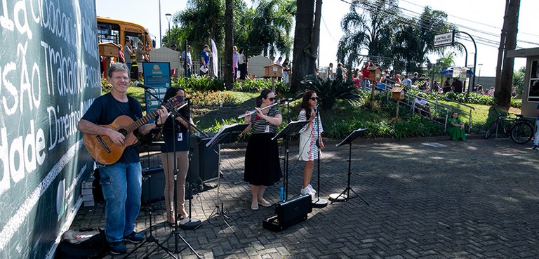 Ao lado de um grande banner com fundo verde e com palavras escritas em branco, que aparece em di...
