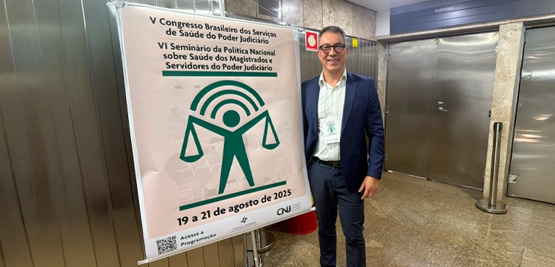 Na fotografia, vê-se um homem de cabelos grisalhos, óculos com armação preta, blazer e calça na ...