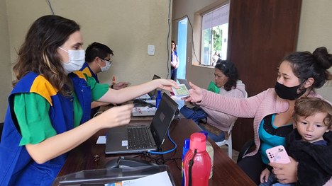 Fotografia de um grupo de indígenas sentados em uma central de atendimento ao eleitor.
