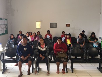 Fotografia de um grupo de indígenas sentados em uma central de atendimento ao eleitor.