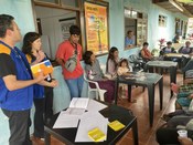 Em um ambiente coberto com paredes azuis, membros de uma equipe de atendimento, dois de coletes ...