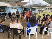 Um grupo diversificado de pessoas está reunido sob uma tenda branca em um ambiente externo, com ...