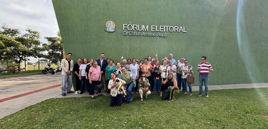 Fotografia na qual se vê uma pessoa pressionando a tecla verde de uma urna eletrônica de cor cla...