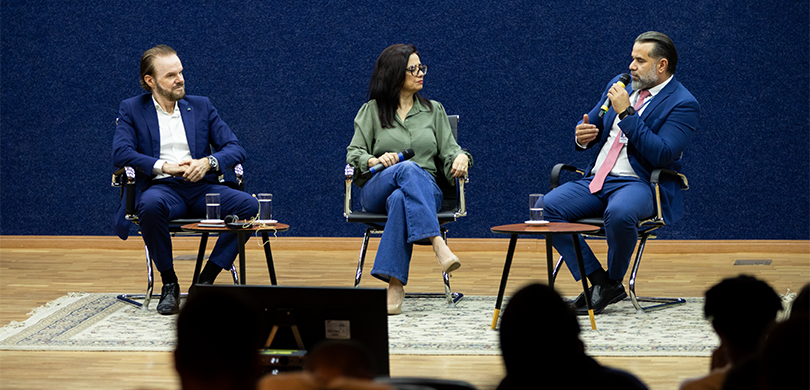 Café Cultural destaca os 30 anos da votação eletrônica no Brasil Fotografia na qual se observam três pessoas sentadas em poltronas pretas sobre um tapete estampa...