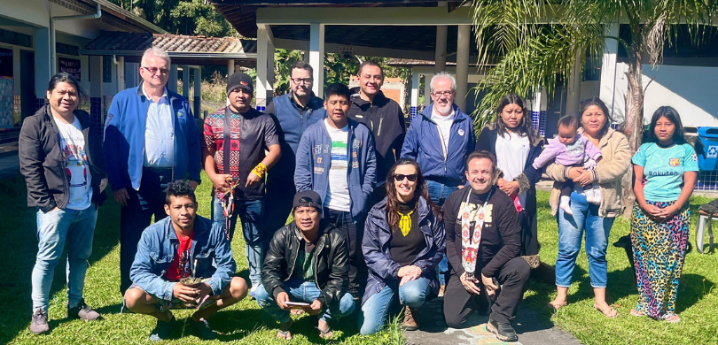 Fotografia dos representantes do TRE-PR ao lado das pessoas indígenas da Ilha da Cotinga posando...