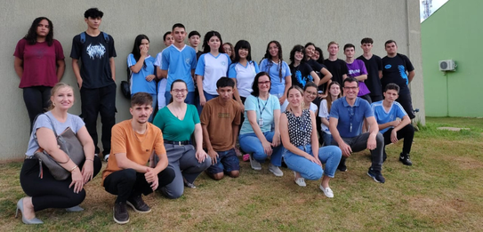 Fotografia que retrata um grupo de jovens posando para uma foto em frente à fachada do Fórum Ele...