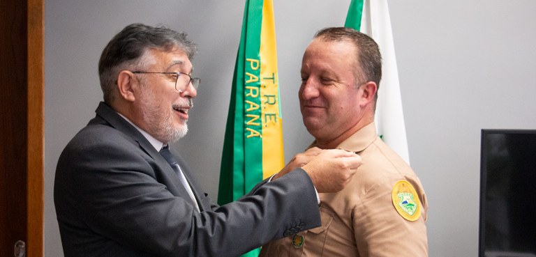 Chefe da Assessoria Militar do TRE-PR é promovido 3 Junior José Vicentin recebendo a divisa de cabo do presidente Coimbra de Moura.