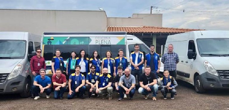 Várias pessoas posam em frente à van adaptada do Programa Cidadania Plena. Dos lados da van, mai...