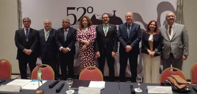 Foto de 6 homens e 2 mulheres, de pé, enfileirados em frente ao banner do evento.