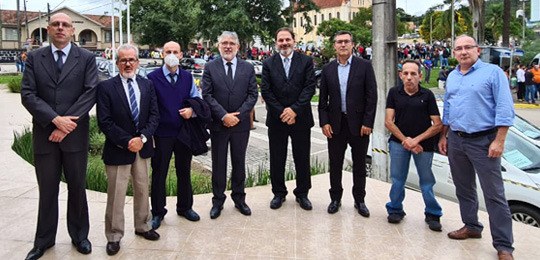 foto de um grupo de pessoas em pé, olhando para a câmera. Elas estão no pátio de uma escola 