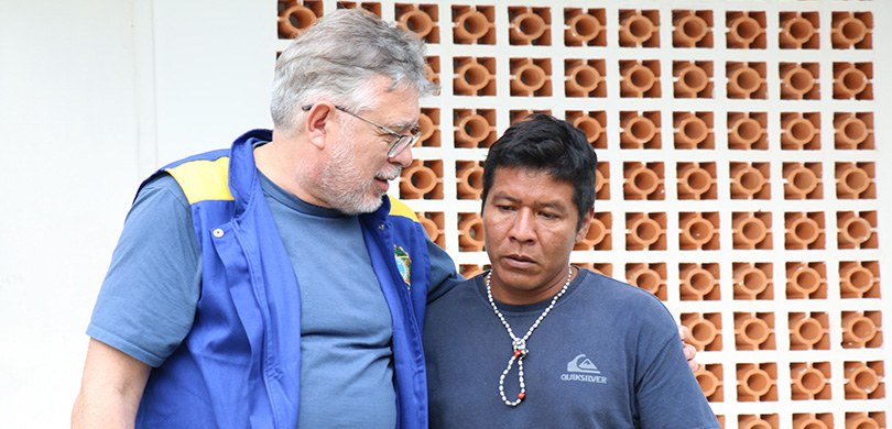 Fotografia de dois homens se abraçando. Um deles é branco e veste o colete da Justiça Eleitoral ...