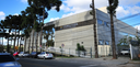 Fotografia do Fórum Eleitoral de Curitiba em um dia de sol, com várias nuvens e céu claro. A con...