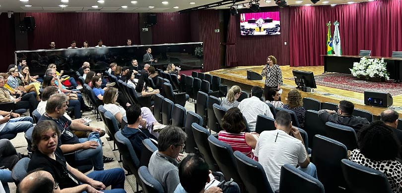 Conversas com Secretarias marcam segundo dia do Kick Off do Projeto Eleições 2024 Uma mulher, com camisa social estampada em preto e branco, de cabelos curtos, fala em um microfo...