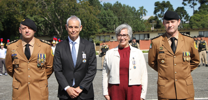 Fotografia em que se observa, em primeiro plano, dois homens e uma mulher em pé, posando para a ...