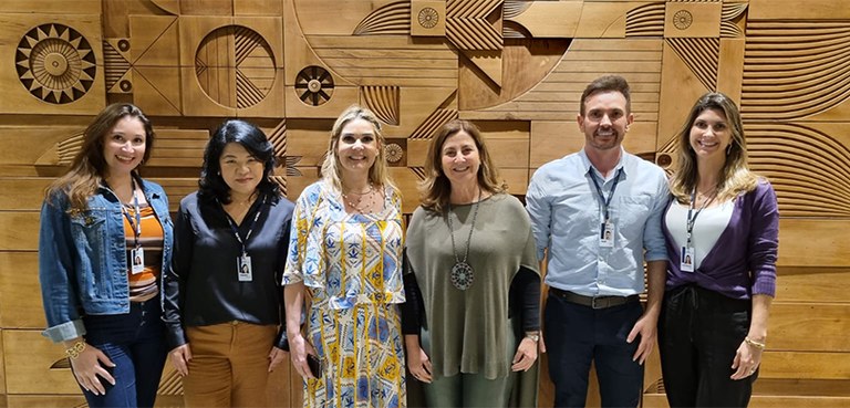 Corregedoria promove capacitação sobre Gestão Processual 2 Fotografia de cinco mulheres e um homem posando sorrindo. Ao fundo, um parede de madeira com fig...