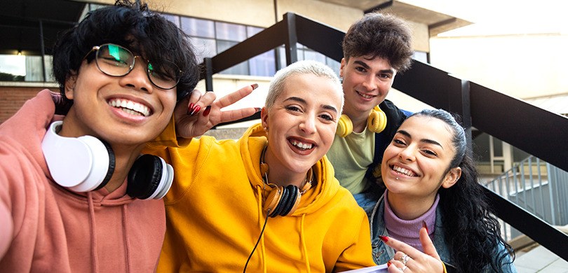 A foto tirada em selfie mostra um grupo de jovens sorrindo para a câmera. São quatro pessoas, qu...