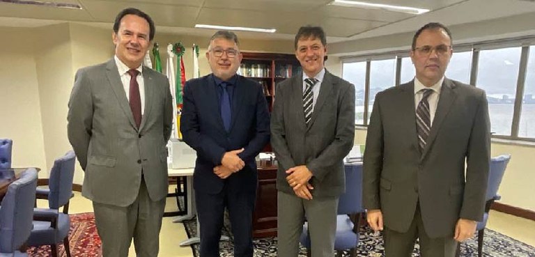 Des. Coimbra de Moura se encontra com presidente do TRF4 2 Fotografia de quatro homens de terno posando sorrindo em uma sala com paredes brancas. Ao fundo,...