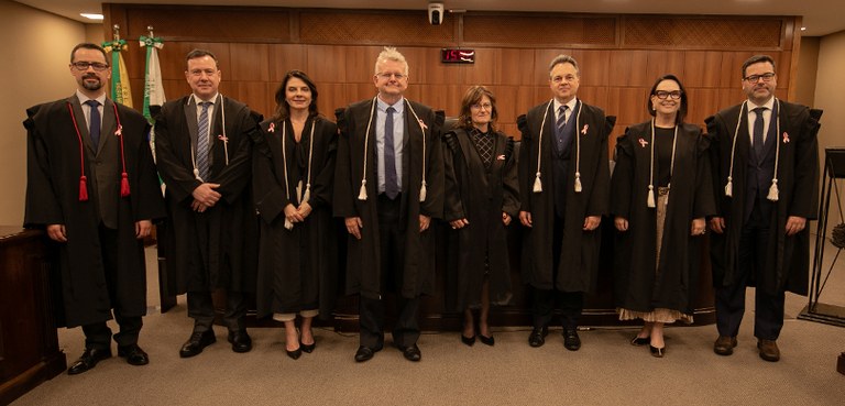 Fotografia em que se veem os membros da Corte do TRE-PR posando, na sala de sessões. Na imagem h...