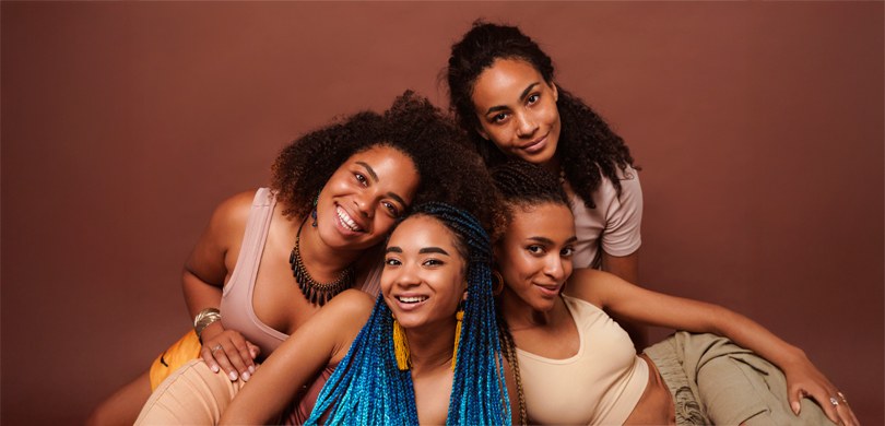 Dia Internacional da Mulher Negra Latino-Americana e Caribenha é comemorado nesta sexta-feira (25) 1 Fotografia de quatro jovens mulheres negras sorrindo posando juntas para a câmera. Elas vestem r...