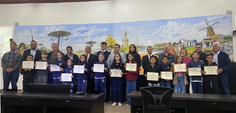 Fotografia de um grupo de 26 pessoas, entre adultos e crianças, alinhadas em duas fileiras e pos...