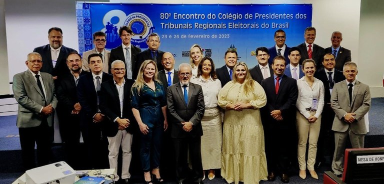 Fotografia de um grupo de 24 pessoas, entre homens e mulheres, posando sorrindo para foto na fre...