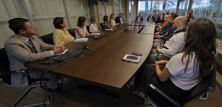 Doutor Valcir Mombach toma posse como novo diretor-geral do TRE-PR 2 Fotografia de uma reunião institucional realizada em uma sala com ampla mesa de madeira escura e...