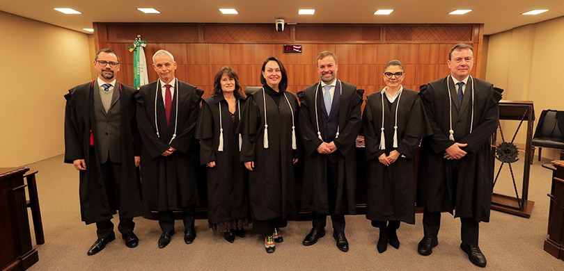 Fotografia em que se observam sete pessoas, quatro homens e três mulheres, em pé e lado a lado, ...