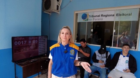 Fotografia de um grupo de indígenas sentados em uma central de atendimento ao eleitor.