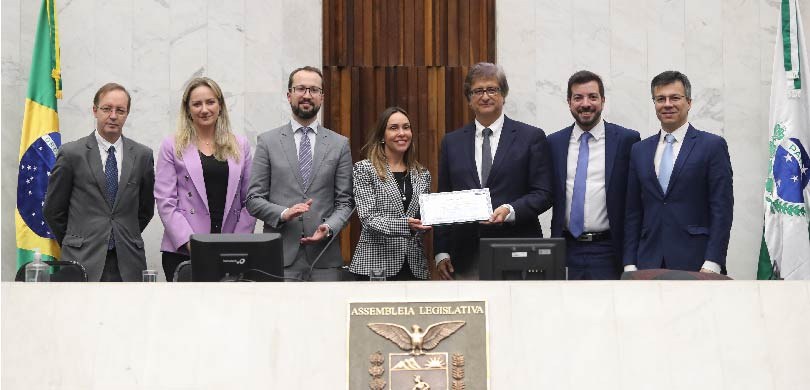 Fotografia de sete pessoas, duas mulheres e cinco homens, posando sorrindo para foto na Assemble...
