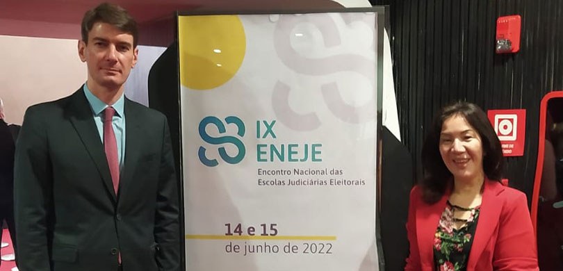 Fotografia do Dr. Roberto Tavarnaro e da servidora Mary Ogawa ao lado do banner do IX ENEJE