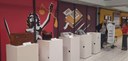 Fotografia na qual se observa um espaço de exposição institucional com objetos históricos e mode...