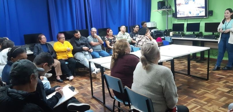 Foto em que aparecem, em uma sala de aula, vários alunos adultos, muitos já idosos, sentados em ...