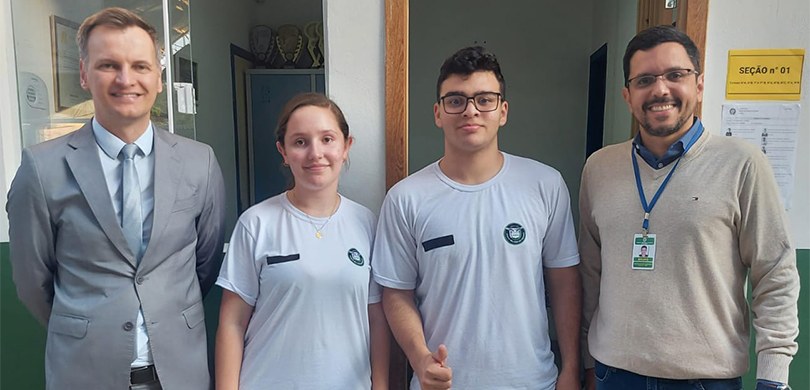 Fotografia de quatro pessoas, três homens e uma mulher, posando sorrindo para foto na frente de ...