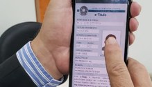 Imagem de duas mãos segurando um celular com o aplicativo e-Título aberto