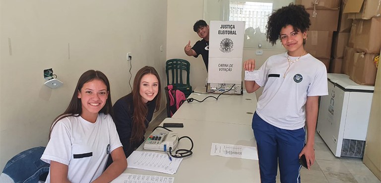 Fotografia de quatro estudantes, três meninas e um menino,  posando para foto durante votação do...
